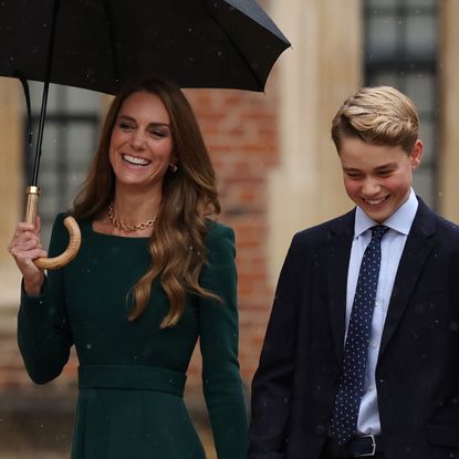 Princess Kate holding an umbrella walking next to Prince George