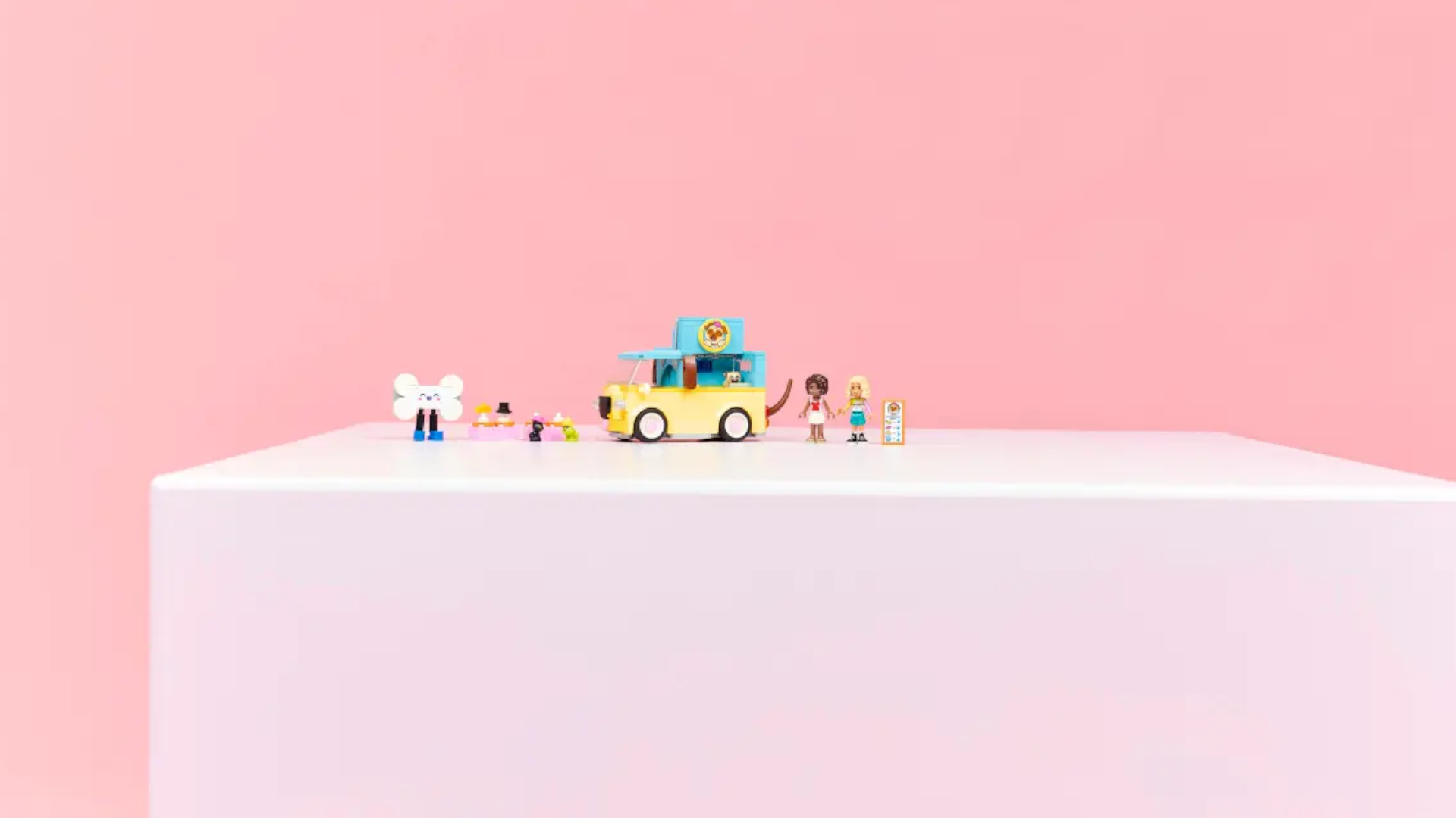 A Lego van and figures on a pink table