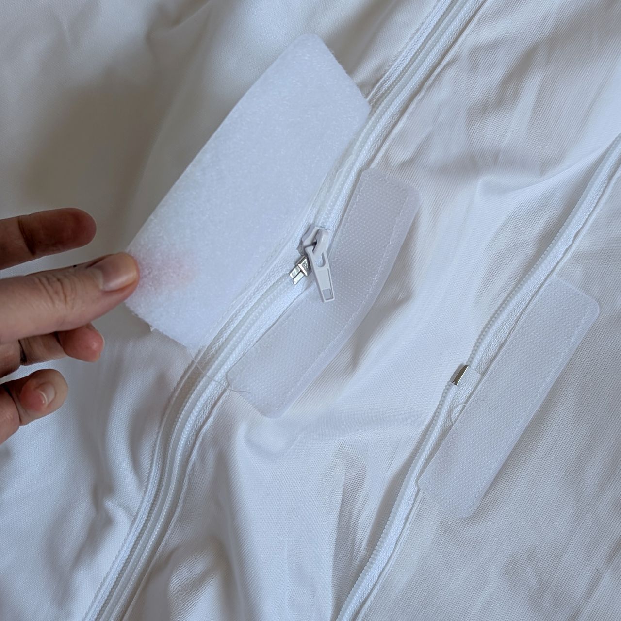 Close up of the zip on the Soak &amp; Sleep Anti Bed Bug Mattress Encasement with a hand holding a velcro flap.
