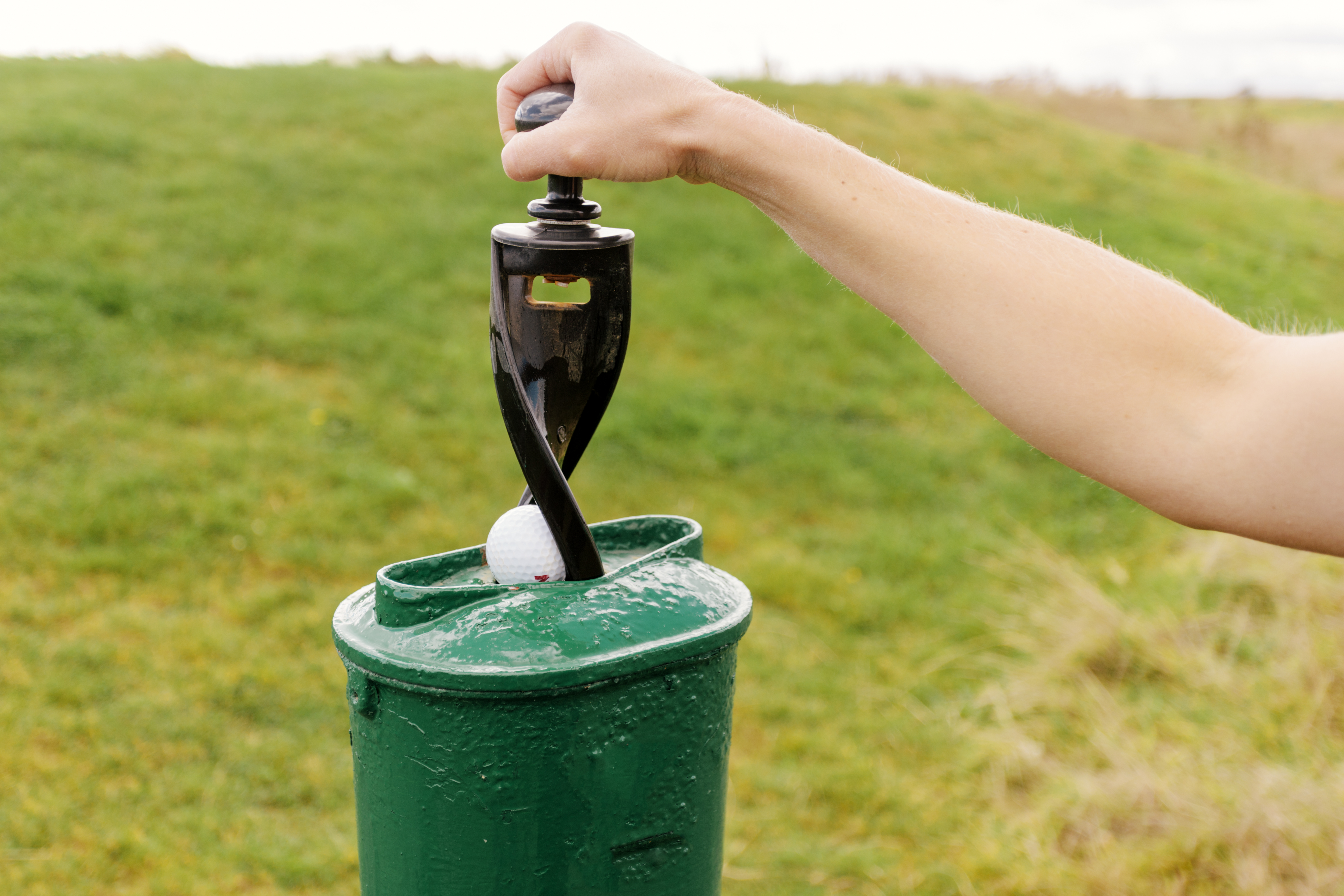 A person uses a golf ball washer
