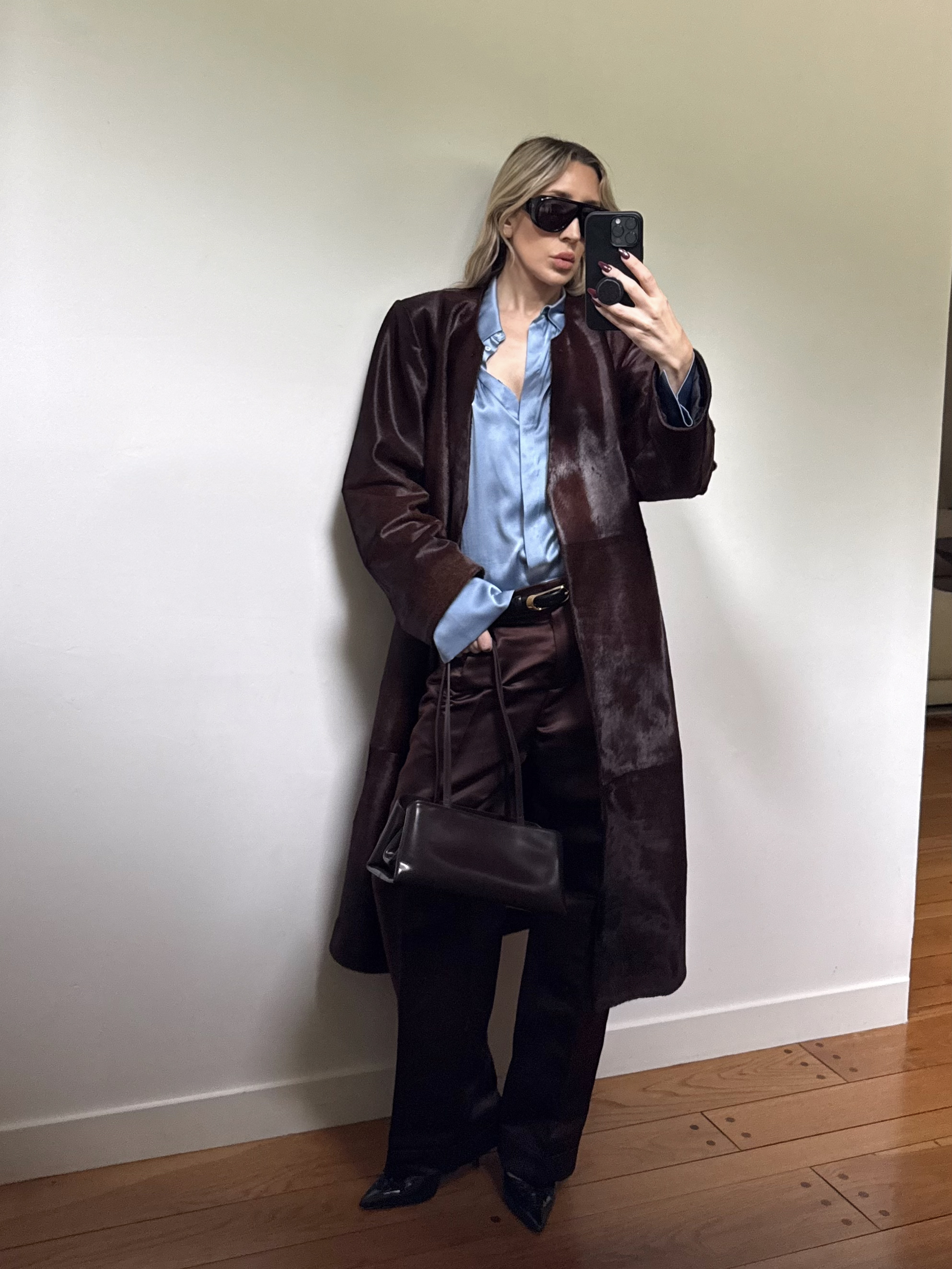 Angela Fink wearing a pony hair coat, a button-down, pants, and shoes