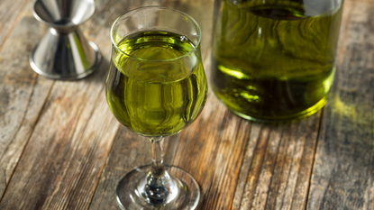 A glass of Chartreuse on a wooden surface