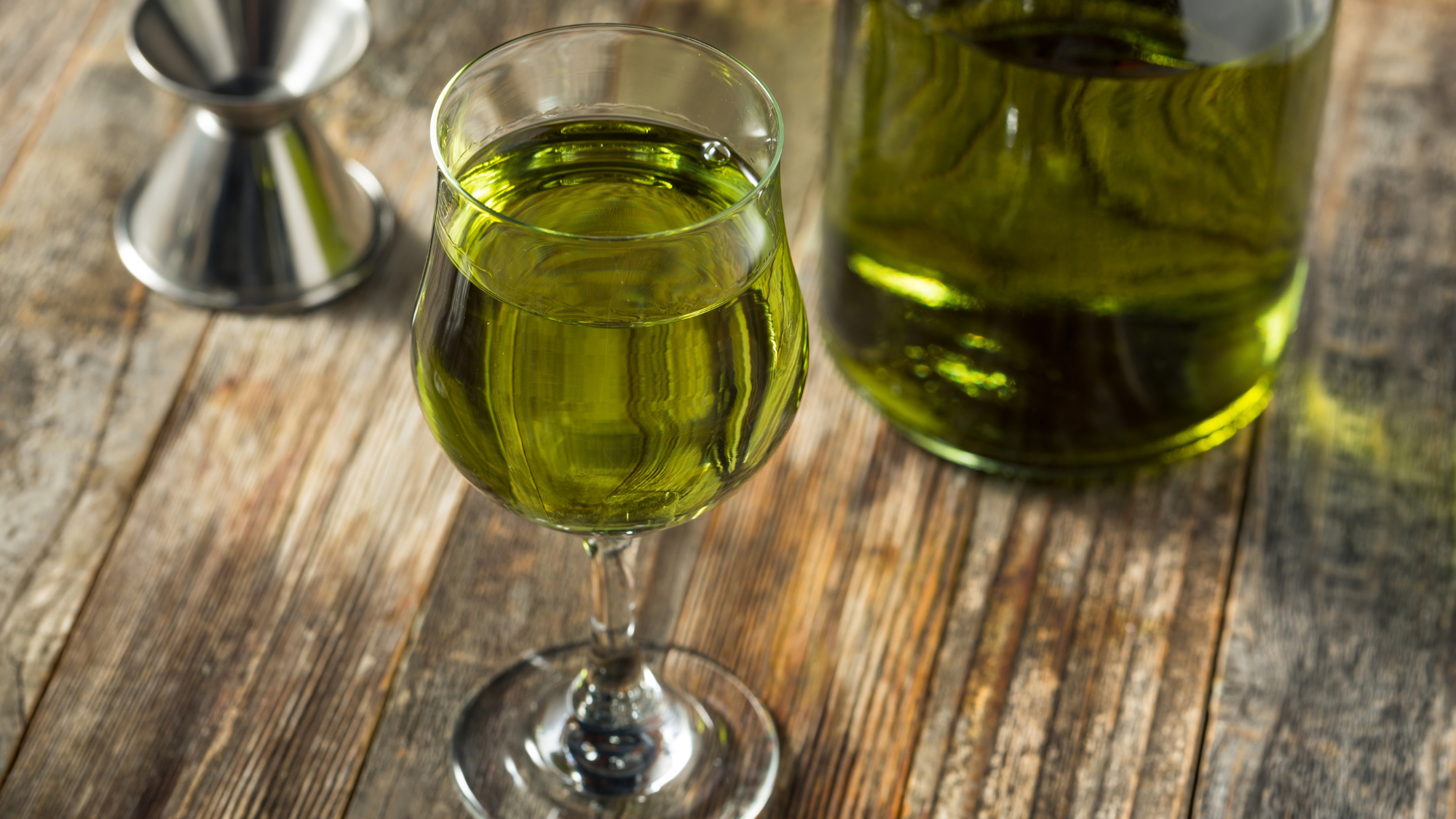 A glass of Chartreuse on a wooden surface 