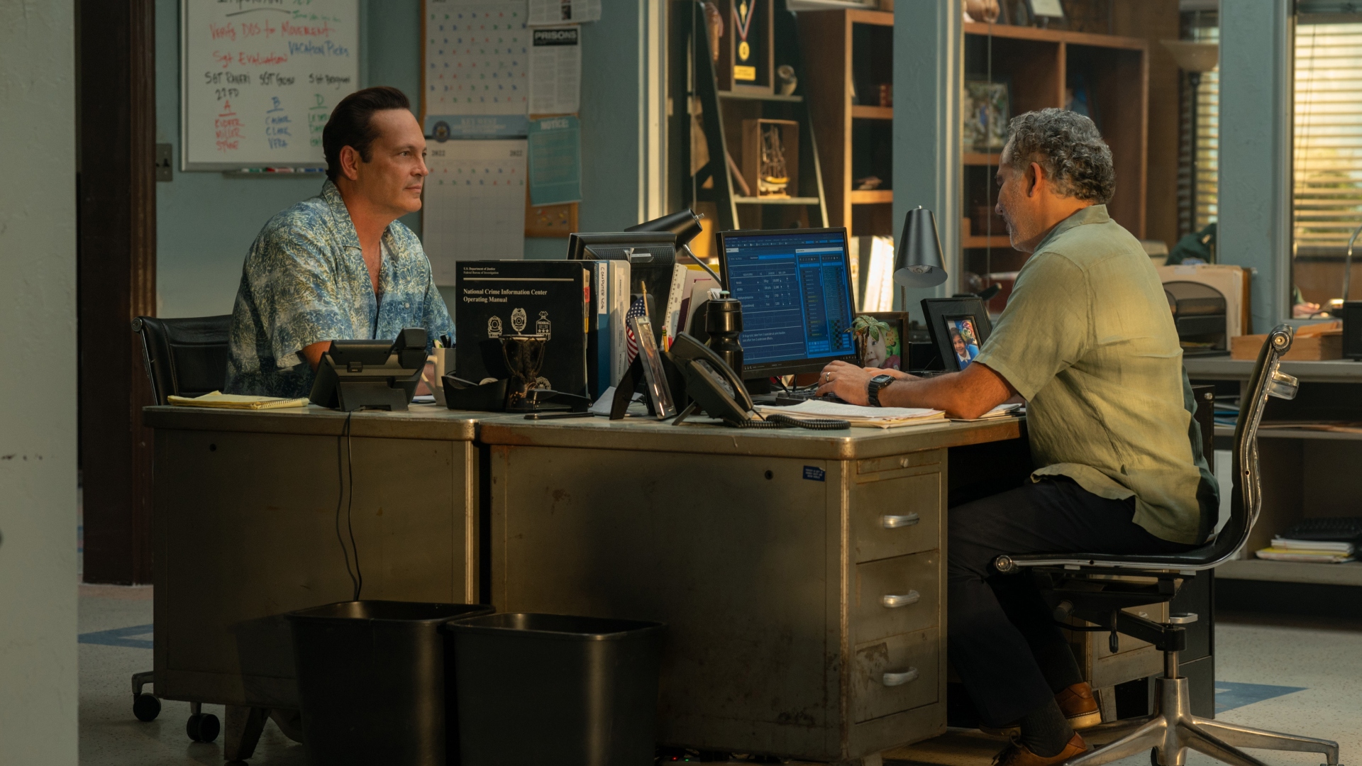 Yancy and Rogelio sit at their desks in Bad Monkey