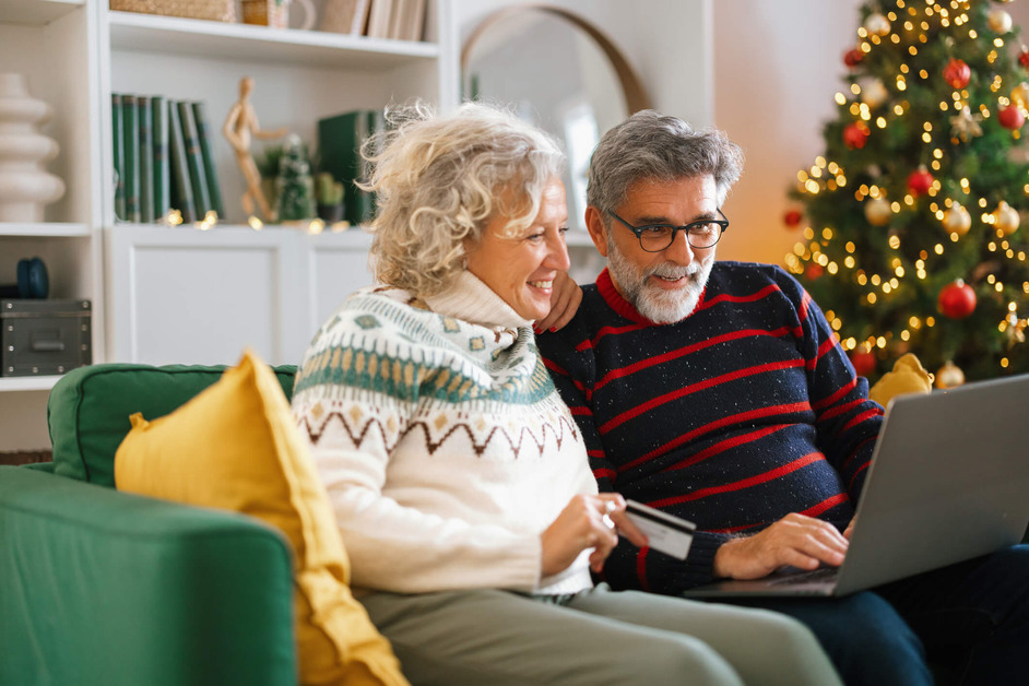 A couple are at home, they are using a laptop to buy Christmas gifts online