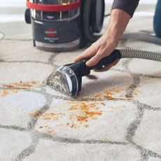 BISSELL SpotClean Pro being used to clean stains from a white carpet