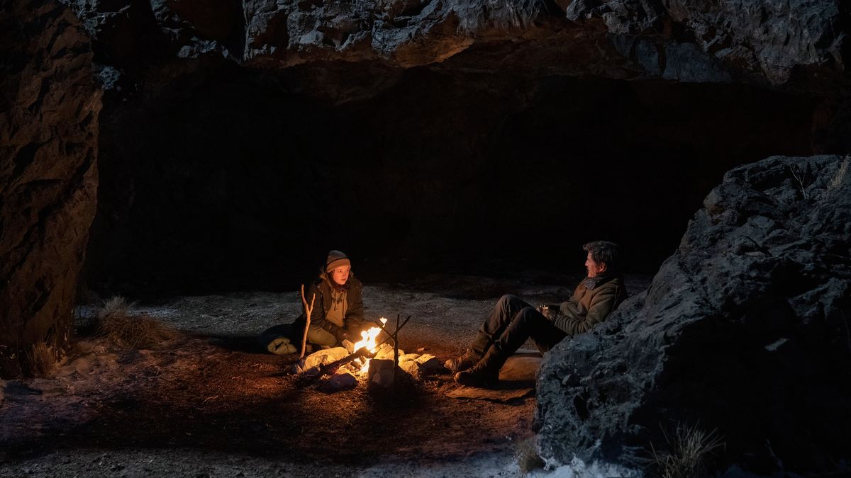 Joel (Pedro Pascal) and Ellie (Bella Ramsey) rest by a campfire in The Last Of Us episode 6.