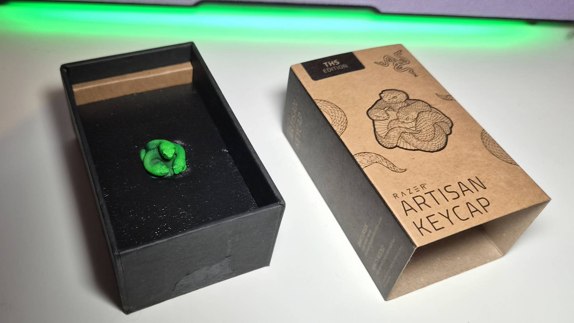 Photo of the Razer Artisan Keycap sitting in its box on a white gaming desk.