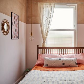 bedroom with two tone walls in blush pink and plaster, bed with patterned bedlinen and a voile window dressing