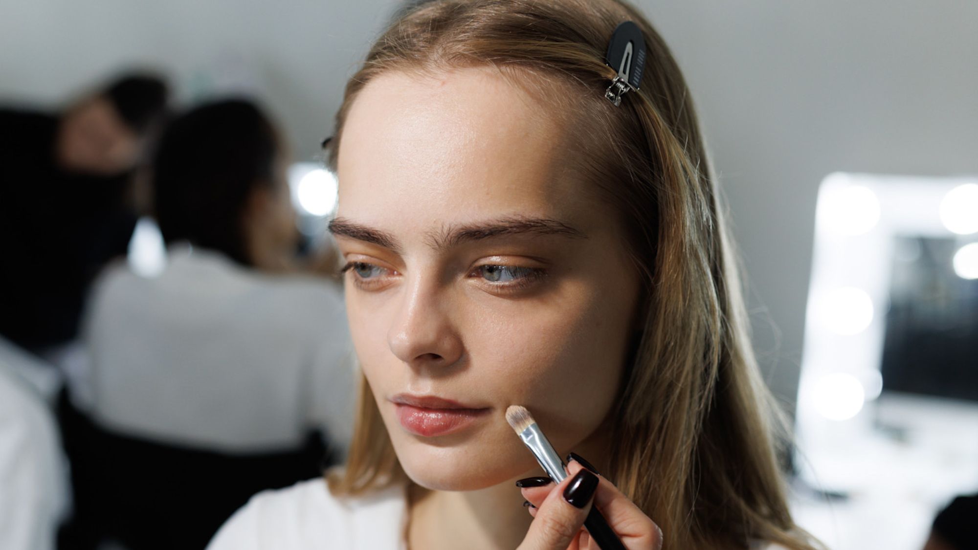 model backstage having foundation applied to her skin