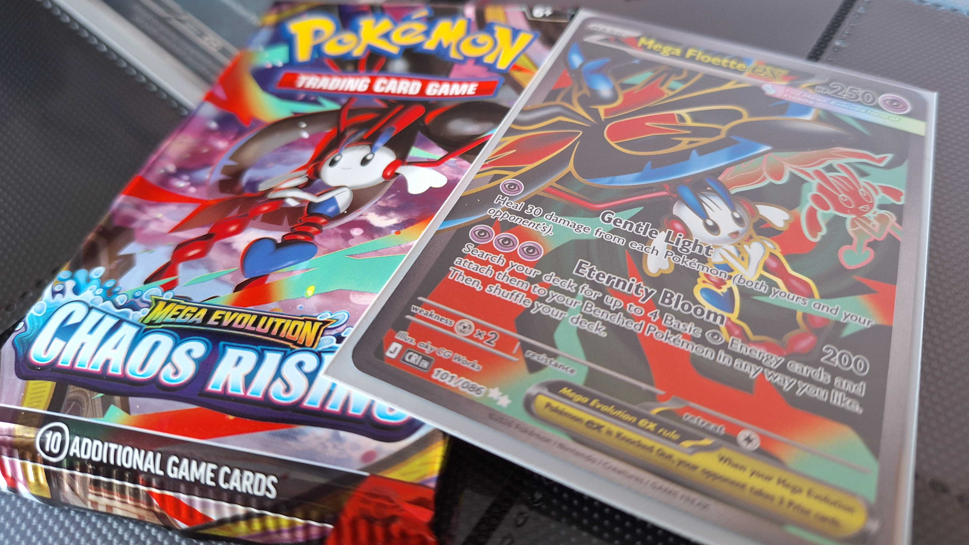 Pokemon Chaos Rising card and booster pack laid out on a dark background