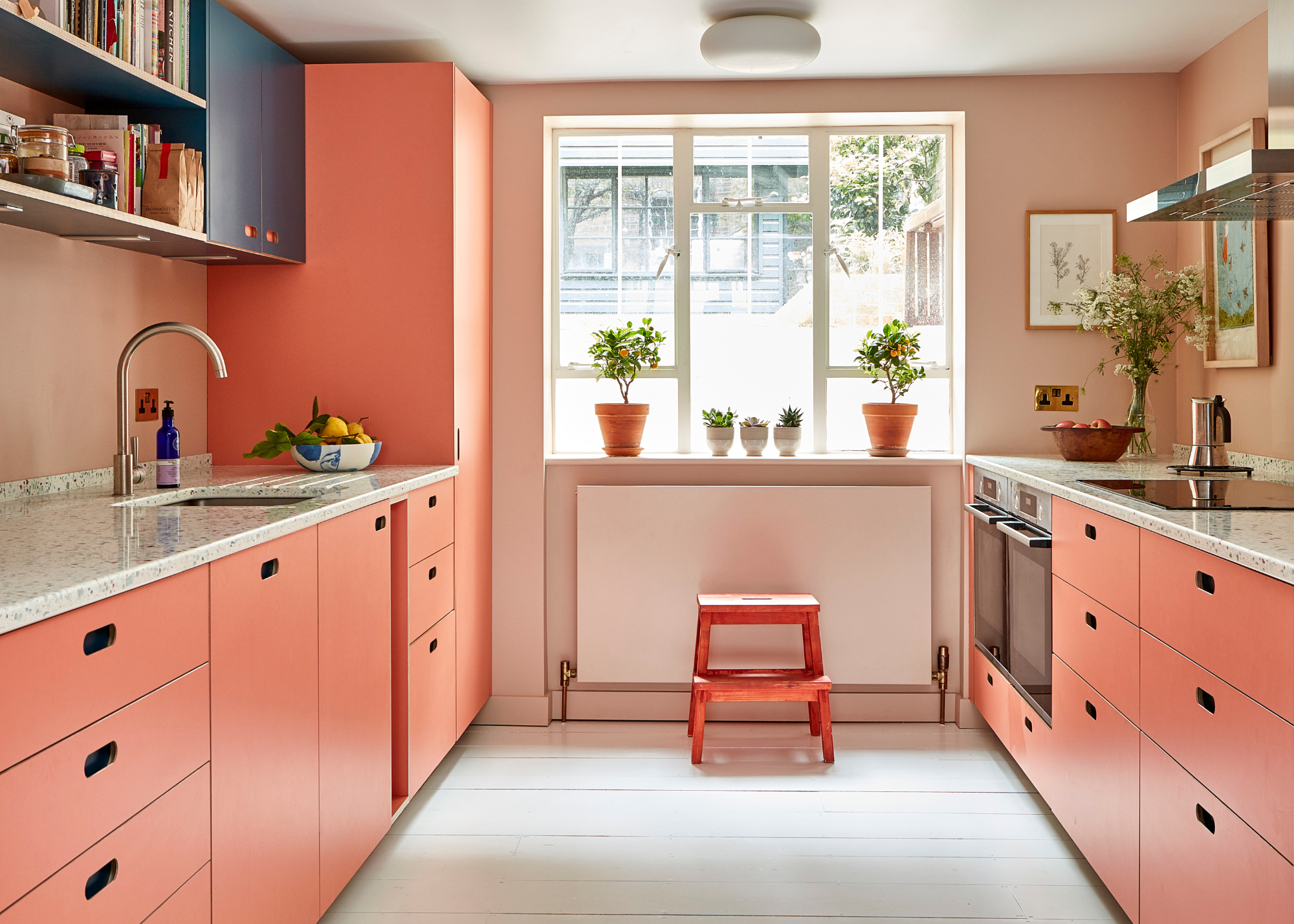 a small coral kitchen with dark navy upper cabinets