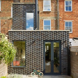 Rear extension to a terraced home with patio doors and large fixed window on to the garden and brick cladding