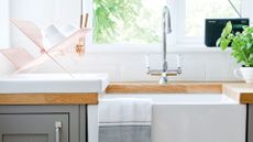 close up of a white Butler kitchen sink encased in wooden worktops in a grey blue kitchen