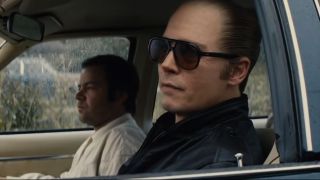 Johnny Depp wearing sunglass in the driver's seat of a parked car in Black Mass.