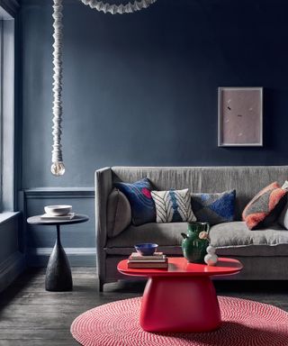A living room with grey sofa, blue walls and red coffee table