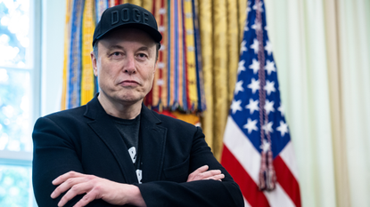 Elon Musk standing in front of an American flag in the Oval Office of the White House in Washington, DC. 