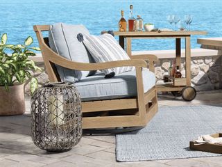 An outdoor chair with bar cart on balcony next to ocean
