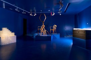 Twisted wood chairs on display in blue-lit gallery