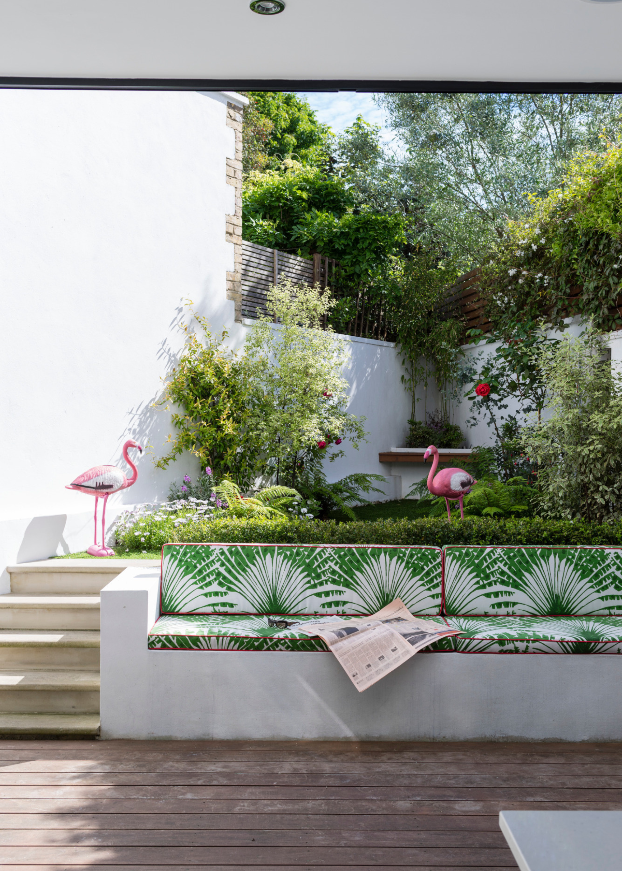 a decking area with built-in seating with steps leading up to a raised garden area