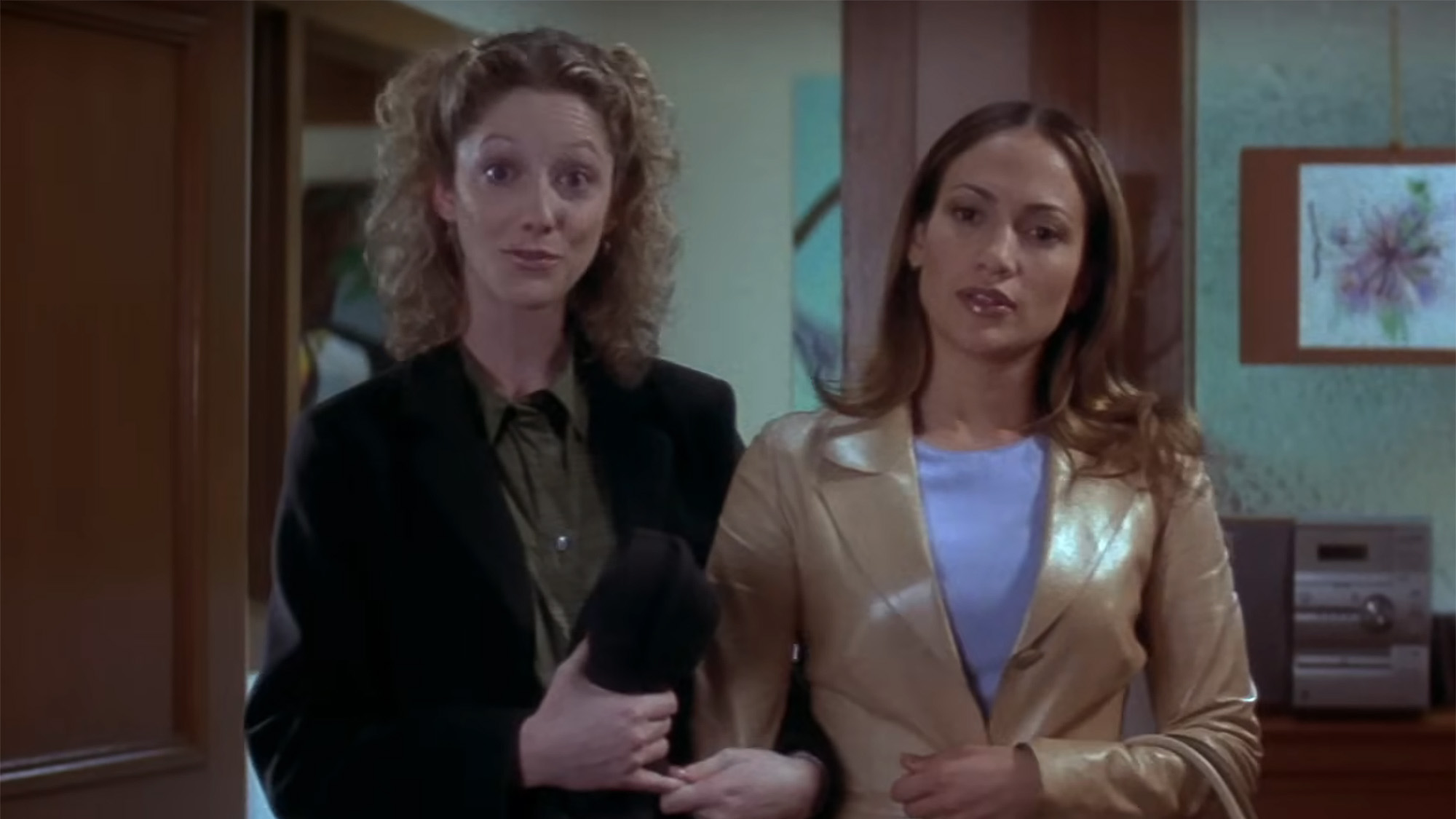Judy Greer and Jennifer Lopez stand side-by-side in a doorway in workwear in The Wedding Planner.