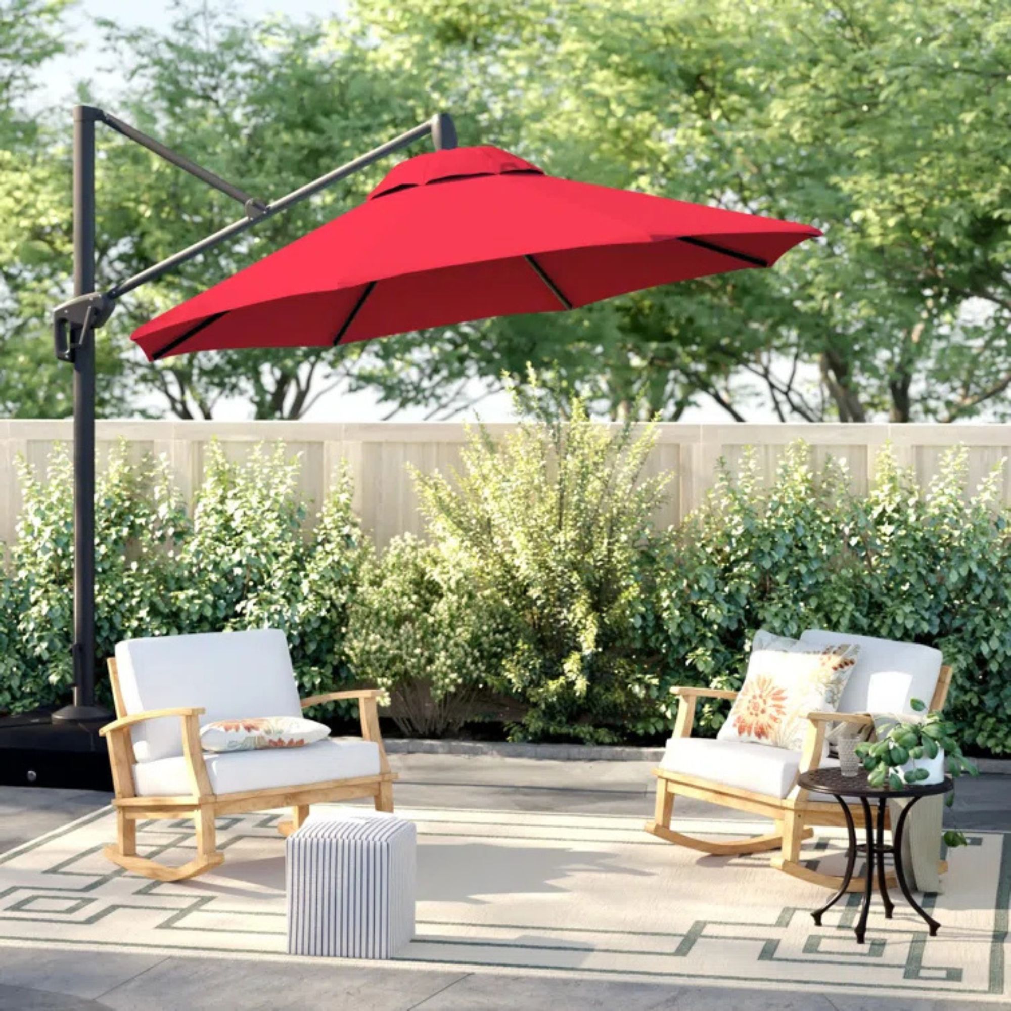 Cassidey Sunbrella on a patio over white chairs against lush greenery. 