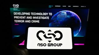 Person holding mobile phone with logo of technology company NSO Group Technologies Ltd. on screen in front of web page