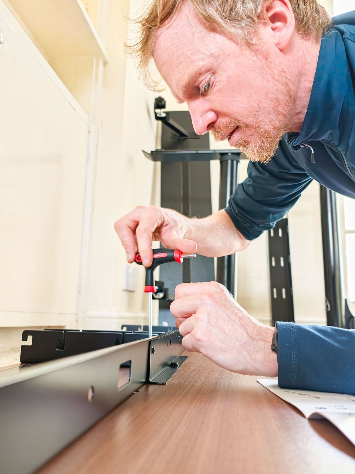 Man assembling the Arozzi Arena Nordico Electric Standing Desk