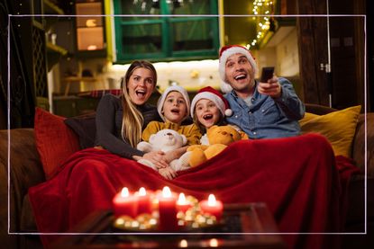 A family sat on the sofa wearing Santa hats while watching the TV