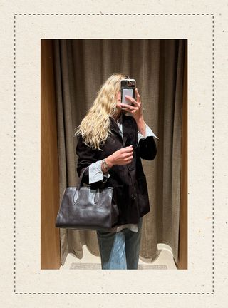 Eliza Huber in the dressing room at Massimo Dutti's new Miami store wearing a brown suede jacket with a striped shirt, jeans, and a brown bag.