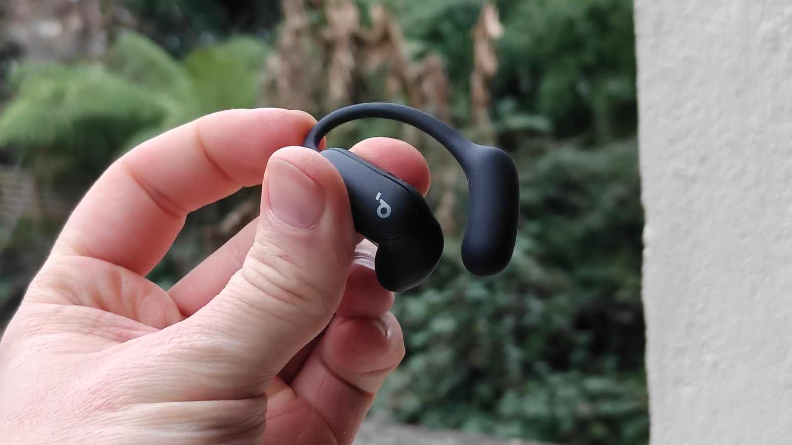 The Soundcore Aerofit 2 Pro in a man's hand, in ANC mode.