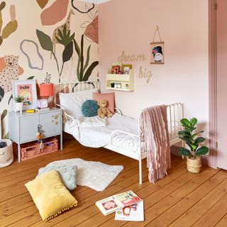 Child's pink bedroom with white metal bed and large mural