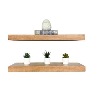 Two wooden floating shelves, one with a book and one with three plants