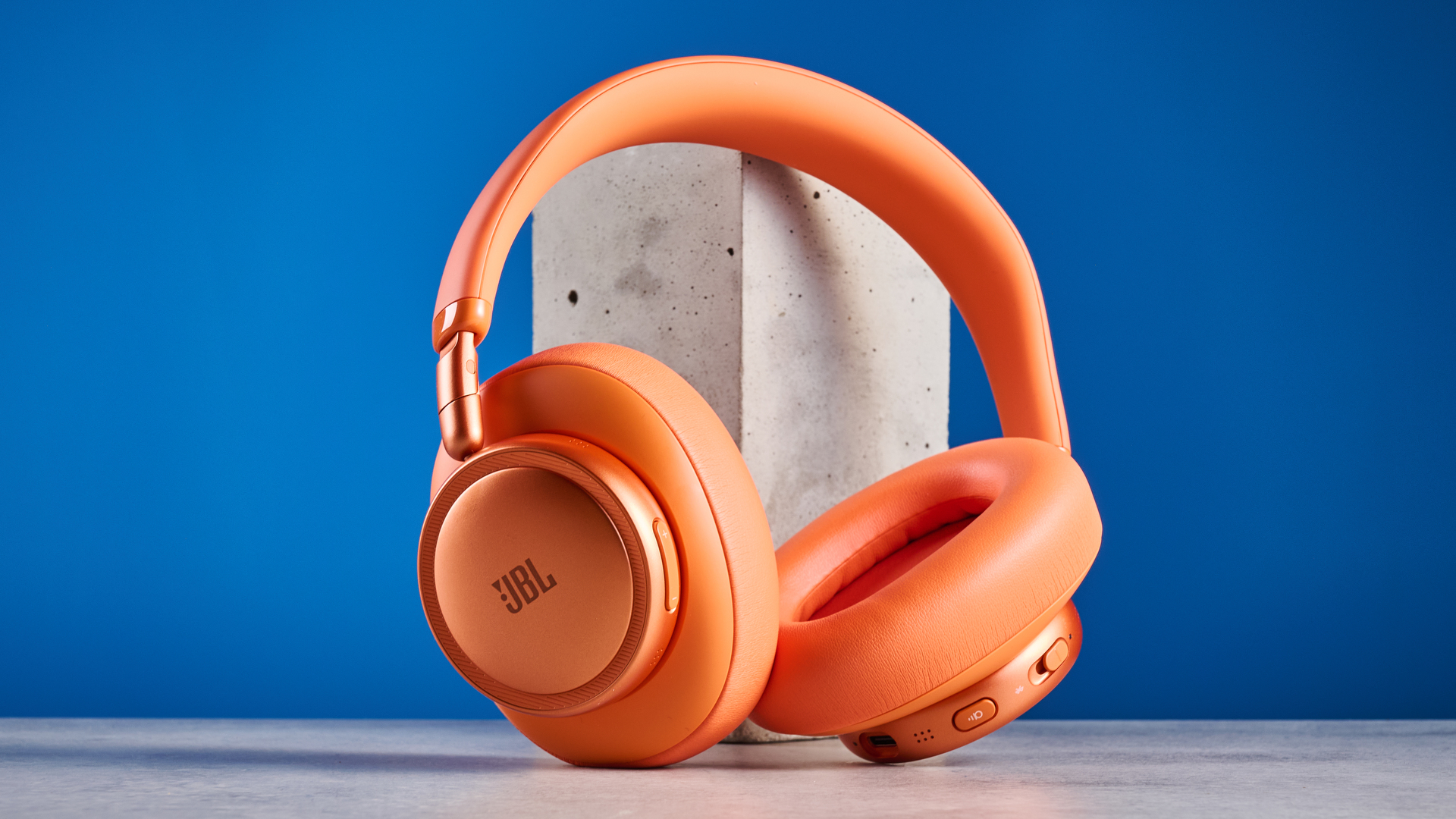 the jbl live 780NC in orange photographed against the blue tom's guide background