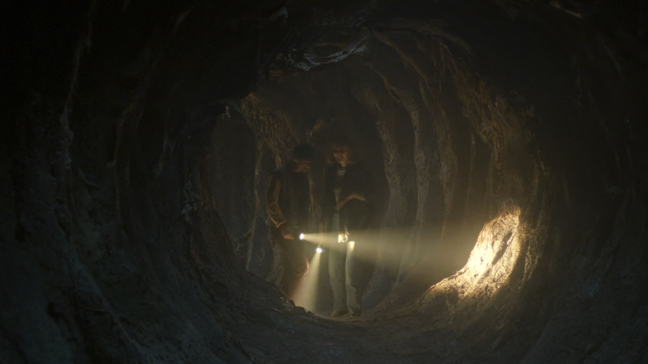 Robin and Will laughing while walking through underground tunnel with flashlights in Stranger Things Season 5 Episode 4