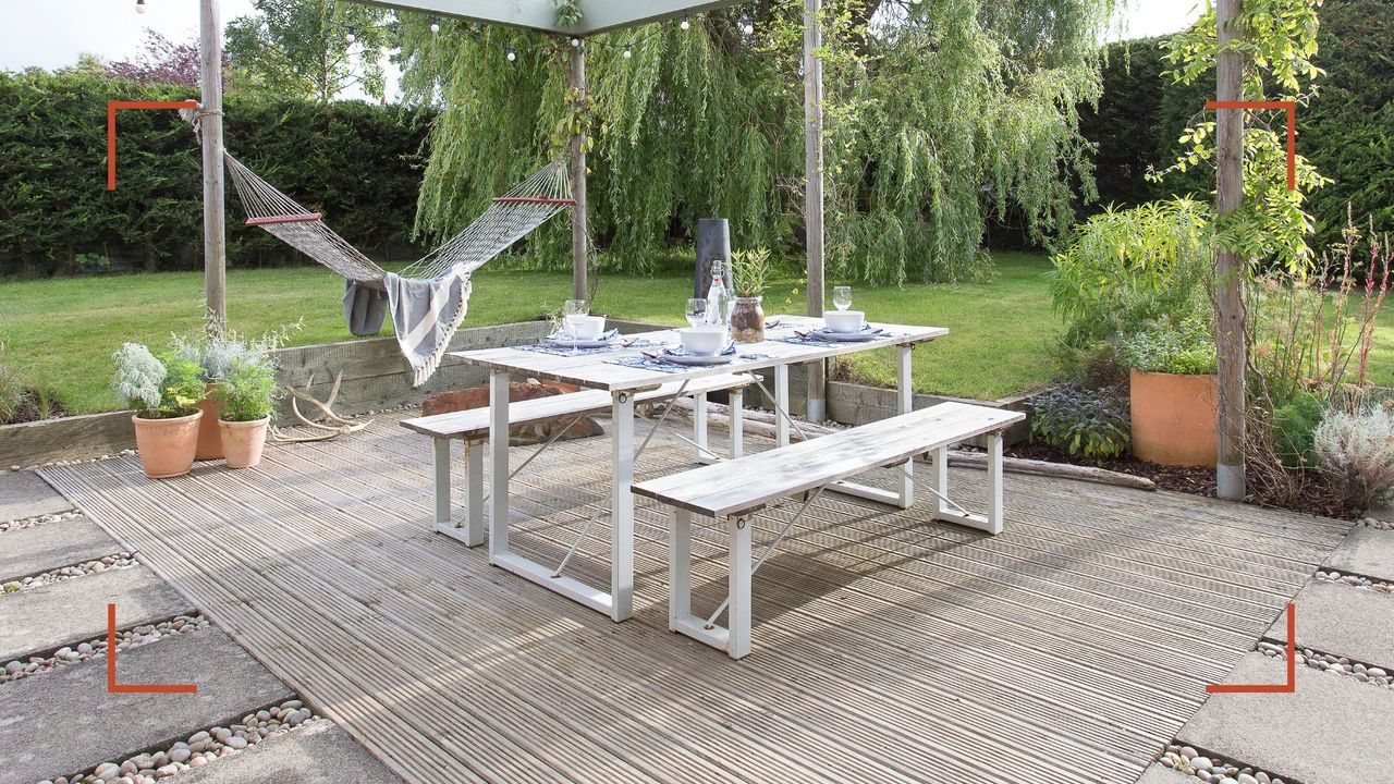 Garden with dining area covered by a pergola with decking to support. gudie on how to clean decking ready for entertaining