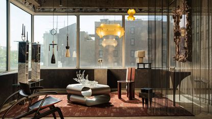 modern living room with chainmail curtain screen, wraparound windows, floating pendant lights, a steel coffee table on a red rug, shelves, sculptural armchairs, and a gilded mirror