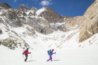 A man and a woman use cross-country skis on white snow in Rocky Mountain National Park