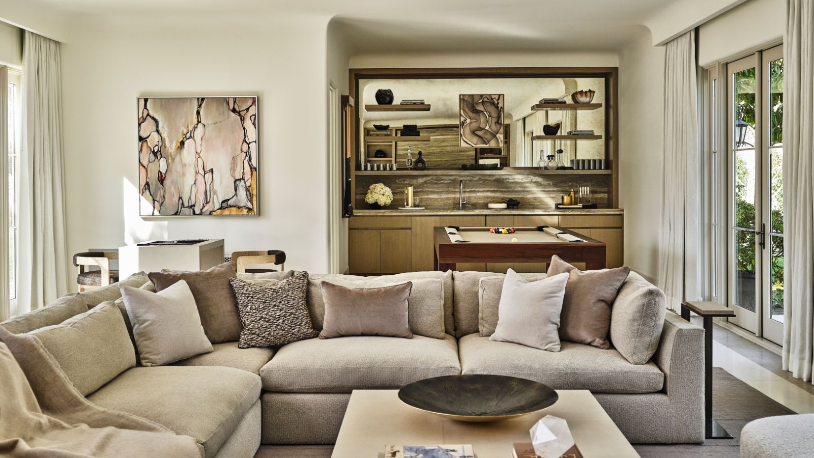 family room with taupe and cream palette taupe sectional sofa and games table and bar behind
