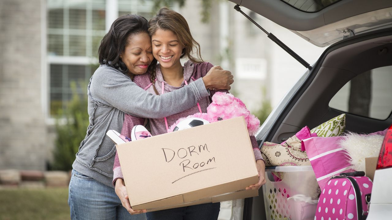 As they&#039;re loading an SUV with boxes, a mom hugs her teen daughter, who&#039;s holding a box labeled &quot;dorm room.&quot;