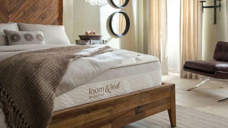 Saatva Loom & Leaf on a bed against cream walls.