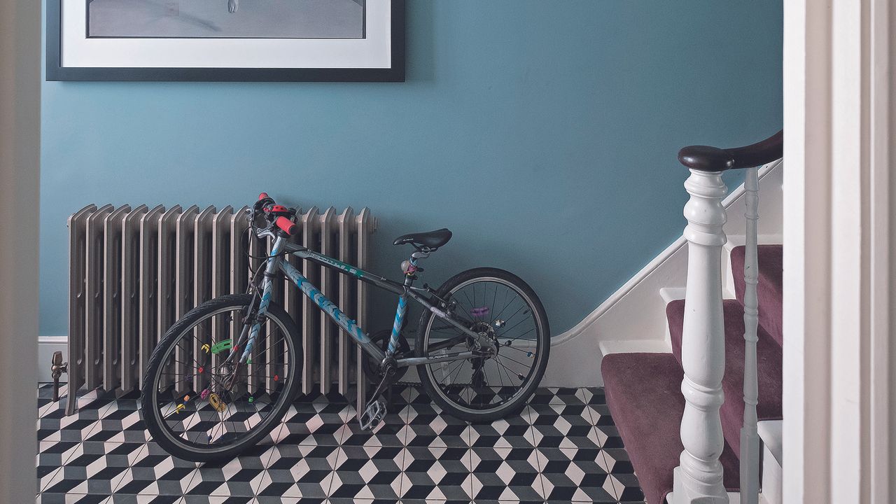 Hallway with black and white tiled floor, grey radiator and bike.