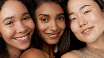 three women with fresh, bright skin smiling together at the camera