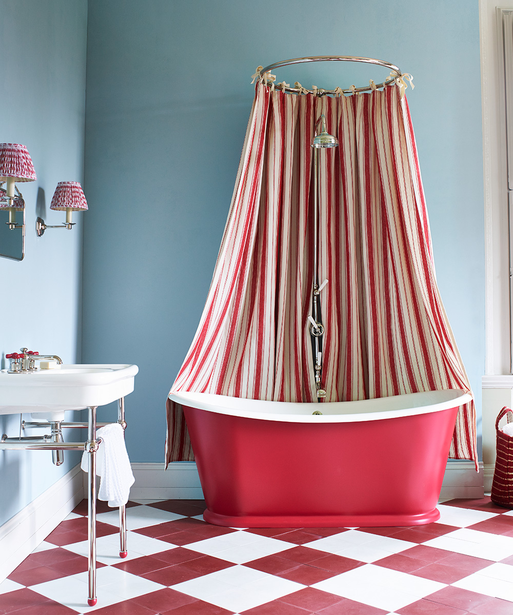 An example of bathroom paint ideas showing a bathroom with a red rolltop bath, light blue walls and a red and white checkered floor