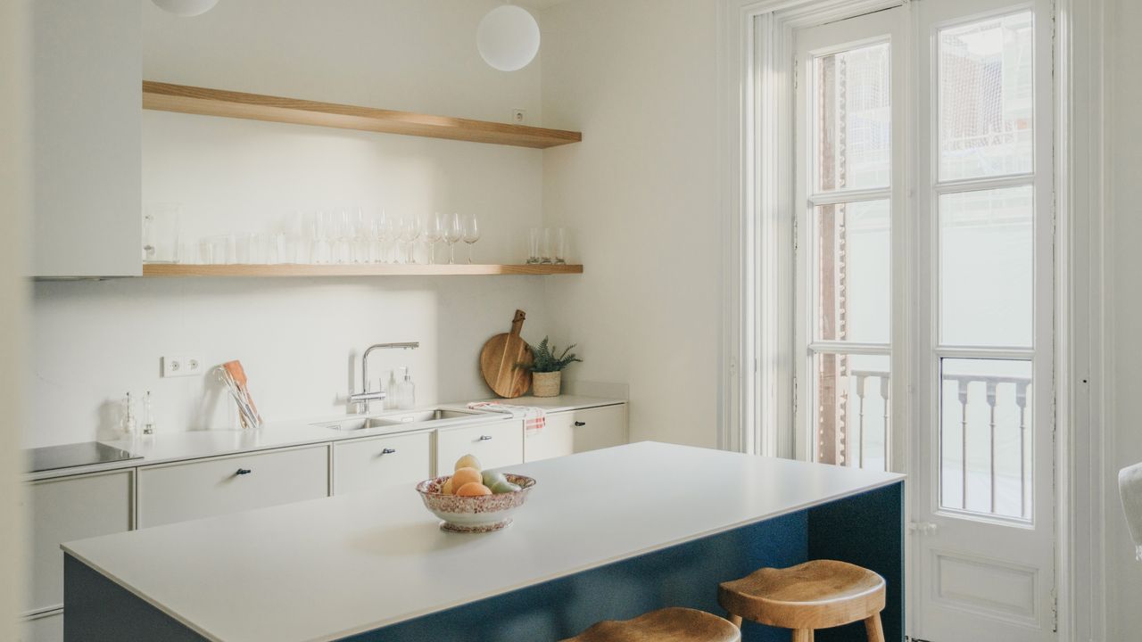 Minimalist small kitchen ideas featuring white shelves, island, wooden accents and open shelving with only clear glass tableware on