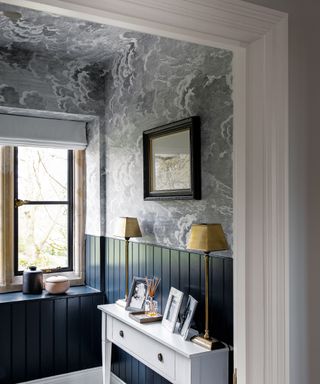 A hallway wallpaper idea with storm-inspired grey wallpaper on the upper half of the wall and ceiling