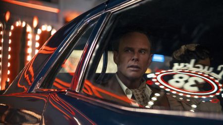 Cooper Howard looking out of a car window as New Vegas lights reflect off the vehicle in Fallout season 2