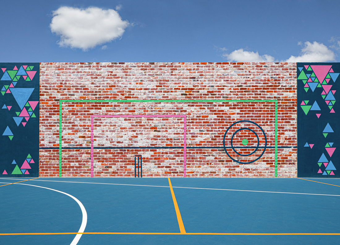 Soccer goals marked on a brick wall behind a basketball court