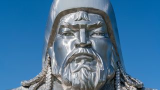 Close-up of Genghis Khan Equestrian Statue. Erdene, Tov province, Mongolia. He has a broad face with a stern expression. He has a short beard and long braided hair which is peaking out from under his hat.