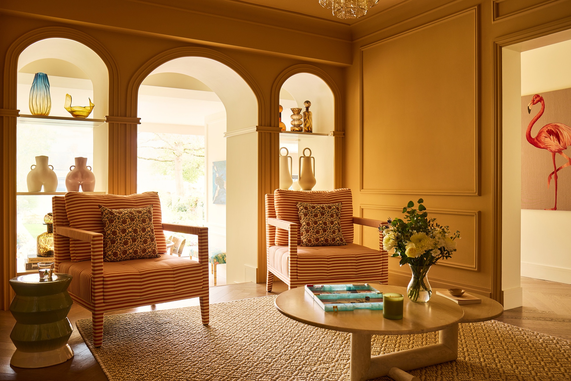 a bright yellow living room with arches into another room, two chairs and a coffee table